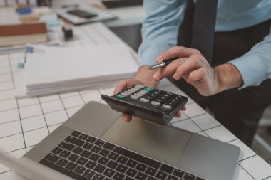 Muhasebeci, ödeme raporuna uygun olarak belgeleri ve mali rakamları kontrol etmek için çok çalışıyor. Bir işadamı özel ofisinde oturuyor, hesaplıyor, şirketini hesaplıyor.