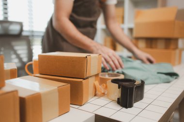 Küçük bir çevrimiçi işletme sahibi müşterilere göndermeden önce doğruluk için kutucukları işaretliyor, paket, bir çalışan müşterilere gönderilmek üzere ürünleri kutulara koyuyor
