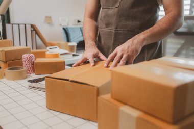 Küçük bir çevrimiçi işletme sahibi müşterilere göndermeden önce doğruluk için kutucukları işaretliyor, paket, bir çalışan müşterilere gönderilmek üzere ürünleri kutulara koyuyor