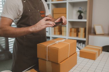 Paketleme odasındaki kutuları kontrol ediyor, küçük bir işletme sahibi kutuları müşterilere, ürünlere, e-ticarete, çevrimiçi satış ve ihracat şirketlerindeki girişimcilere göndermek için hazırlıyor.