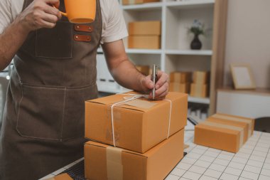 Paketleme odasındaki kutuları kontrol ediyor, küçük bir işletme sahibi kutuları müşterilere, ürünlere, e-ticarete, çevrimiçi satış ve ihracat şirketlerindeki girişimcilere göndermek için hazırlıyor.