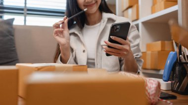 Girişimci müşteri siparişi için paket topluyor. Küçük bir işletmesi var. Sme, odada bir sürü paket var.