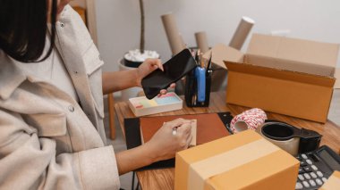 Girişimci müşteri siparişi için paket topluyor. Küçük bir işletmesi var. Sme, odada bir sürü paket var.