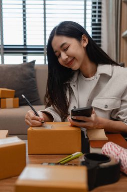 Girişimci müşteri siparişi için paket topluyor. Küçük bir işletmesi var. Sme, odada bir sürü paket var.