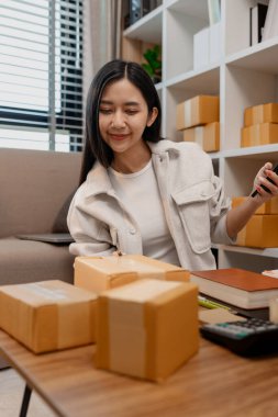 Girişimci müşteri siparişi için paket topluyor. Küçük bir işletmesi var. Sme, odada bir sürü paket var.