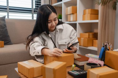 Girişimci müşteri siparişi için paket topluyor. Küçük bir işletmesi var. Sme, odada bir sürü paket var.