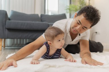 Bir baba bebeğiyle kaliteli zaman geçirir. Yumuşak bir paspasın üzerinde nazik bakım ve eğlenceli anlarda oynayıp bağ kurar. Bebek karın zamanını ve emzik kullanımını destekliyor..