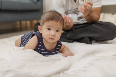 Bir baba bebeğiyle kaliteli zaman geçirir. Yumuşak bir paspasın üzerinde nazik bakım ve eğlenceli anlarda oynayıp bağ kurar. Bebek karın zamanını ve emzik kullanımını destekliyor..