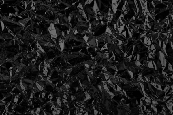 Shiny black foil texture background, pattern of wrapping paper with crumpled and wavy.