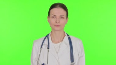 Serious Young Female Doctor on Green Background 