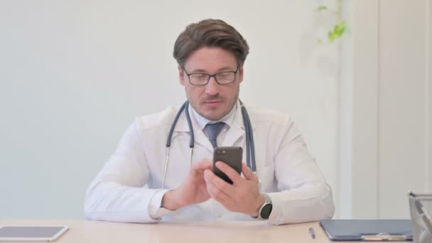クリニックでスマホを使う中高年医師 — ストック動画
