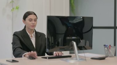 Genç İşkadını Masaüstü Bilgisayarı kullanırken Kameraya Bakıyor