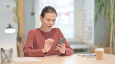 Successful Young Woman Celebrating Win on Smartphone