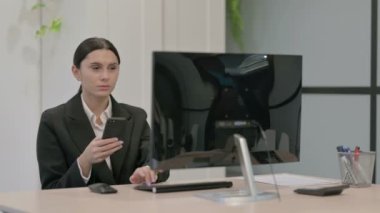 Genç İşkadını Masaüstü Bilgisayarı kullanırken Telefonda Konuşuyor