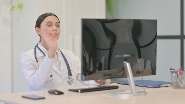 若い女性医師がクリニックのデスクトップコンピュータ上でビデオ通話で話す — ストック動画