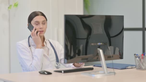 Young Female Doctor Talking Phone While Working Desktop Computer — Stock Video