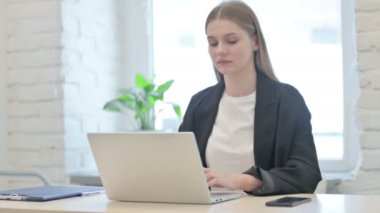 İş kadını dizüstü bilgisayar kullanırken kamerayı işaret ediyor