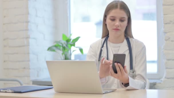 Νεαρή Γυναίκα Γιατρός Χρησιμοποιώντας Smartphone Κατά Χρήση Laptop — Αρχείο Βίντεο
