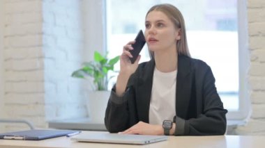 İş kadını ofiste telefonla konuşuyor. 