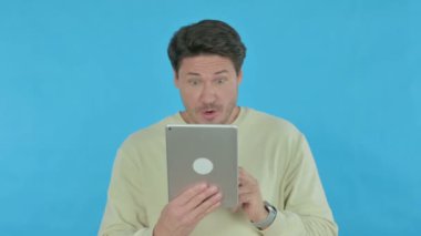 Handsome Young Man Reacting to Loss on Tablet on Blue Background