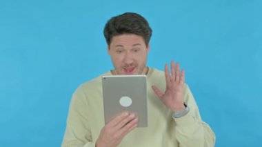 Video Call on Tablet by Handsome Young Man on Blue Background