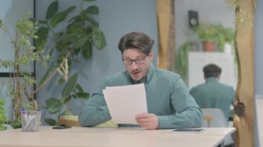 Middle Aged Businessman Celebrating Success while Reading Documents at Work