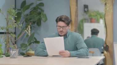 Middle Aged Businessman Reading Documents at Work, Paperwork