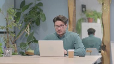 Middle Aged Businessman Shaking Head in Rejection while Working on Laptop