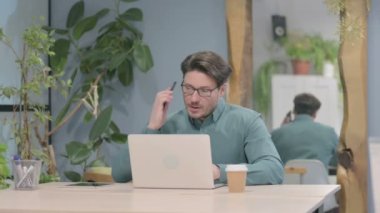 Middle Aged Businessman Talking on Phone while using Laptop