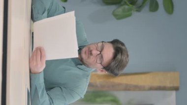 Vertical Video of Mature Adult Man Reading Documents in Office, Paperwork