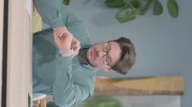 Vertical Video of Mature Adult Man Browsing Internet on Smartwatch in Office