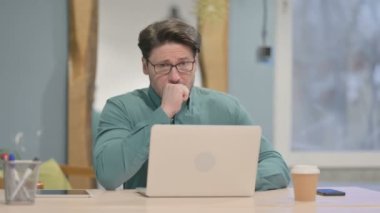 Mature Adult Businessman Coughing while Working on Laptop