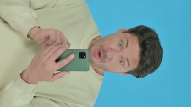 Handsome Young Man Loss Smartphone Blue Background Vertical Video — Αρχείο Βίντεο