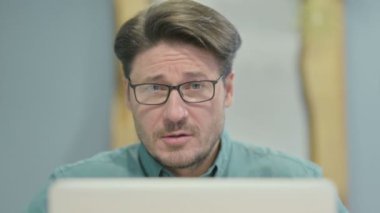 Close Up of Businessman Smiling at Camera while using Laptop