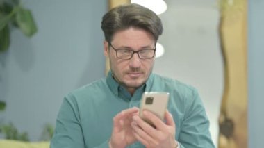 Excited Middle Aged Businessman Celebrating Win on Smartphone