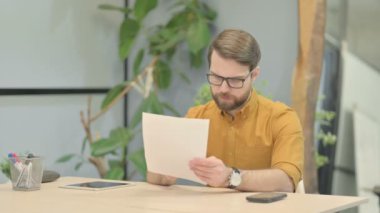 Middle Aged Businessman Reading Documents at Work, Paperwork