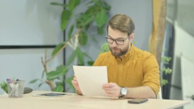 Middle Aged Businessman Celebrating Success while Reading Documents at Work