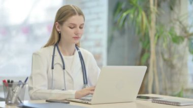 Young Doctor Smiling at Camera while using Laptop