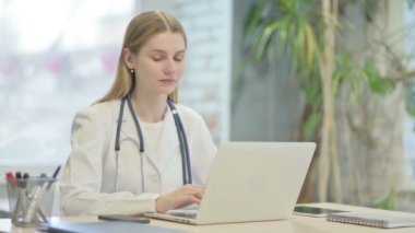 Young Doctor Shaking Head in Rejection while Working on Laptop