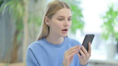 Portrait of Casual Young Woman Upset by Loss on Smartphone