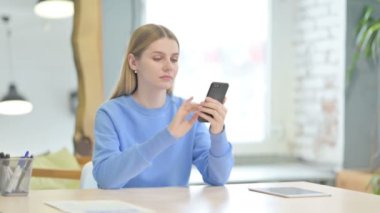 Young Woman Browsing Internet on Smartphone at Work