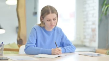 Young Woman Writing Letter while Sitting at Work