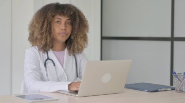 Kadın Afrikalı Doktor Klinikte otururken Kameraya Bakıyor