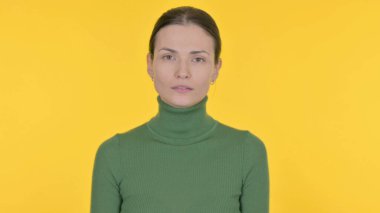 Sarı arka planda ciddi bir genç kadın.