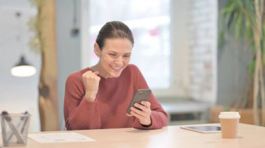 Successful Young Woman Celebrating Win on Smartphone