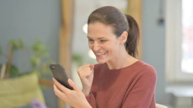 Excited Young Woman Celebrating Win on Smartphone