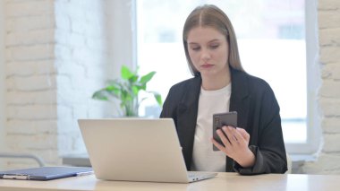 İş kadını dizüstü bilgisayar kullanırken Smartphone kullanıyor