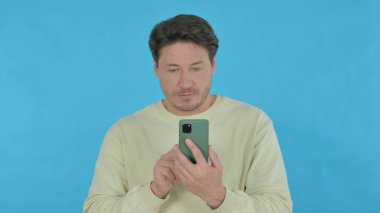 Handsome Young Man Browsing Smartphone on Blue Background