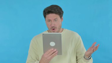 Handsome Young Man Reacting to Loss on Tablet on Blue Background