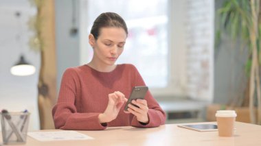 Young Woman Browsing Internet on Smartphone in Office